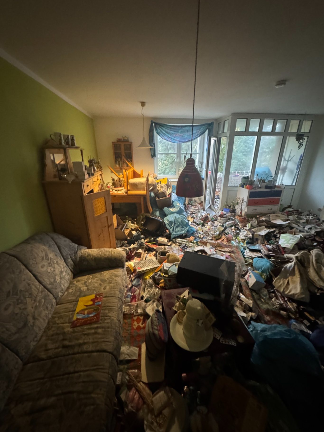 Unordentlicher Wohnraum mit einem überfüllten Boden und unorganisierten Möbeln.